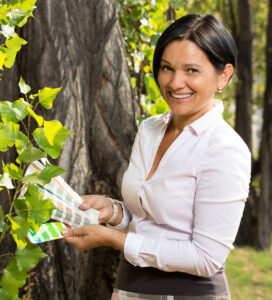 Mejra Weiss mit Drucksorten in der Hand vor einem Baum