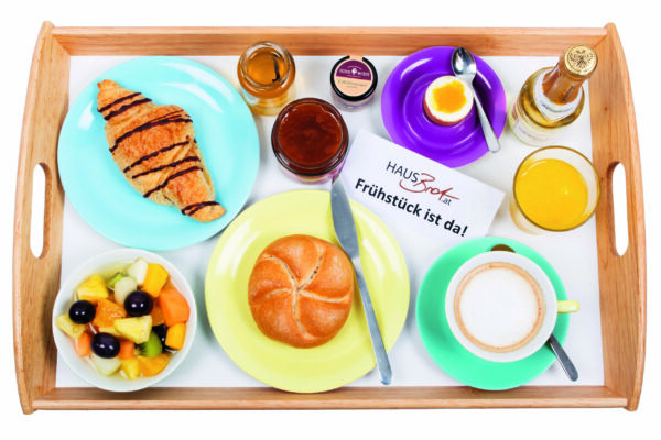 Tablett mit Semmel, Croissant, Obstsalat, Kaffee, Ei, Orangensaft und Aufstrich